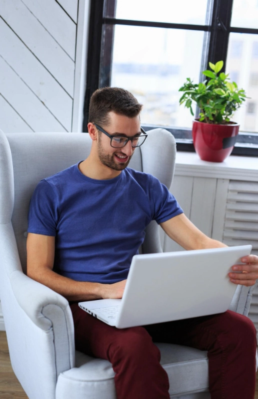A man sitting at home, engaged in a virtual therapy session on his laptop.