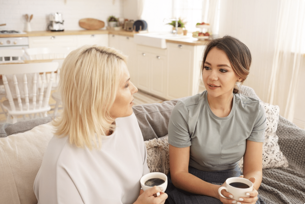 A woman looking thoughtful and serious while opening up emotionally to a supportive friend on a couch.