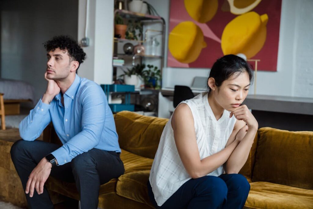 A stressed couple sitting on a couch facing away