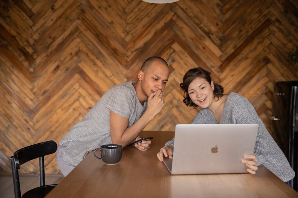 A young couple sitting at home in a cozy setting, engaged in a virtual pre-marriage counseling session via laptop.