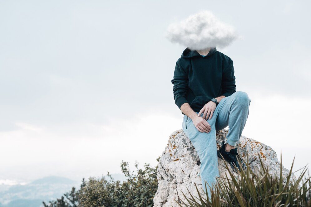 Man sitting on a rock with a cloud over his head, representing the inability to form mental images