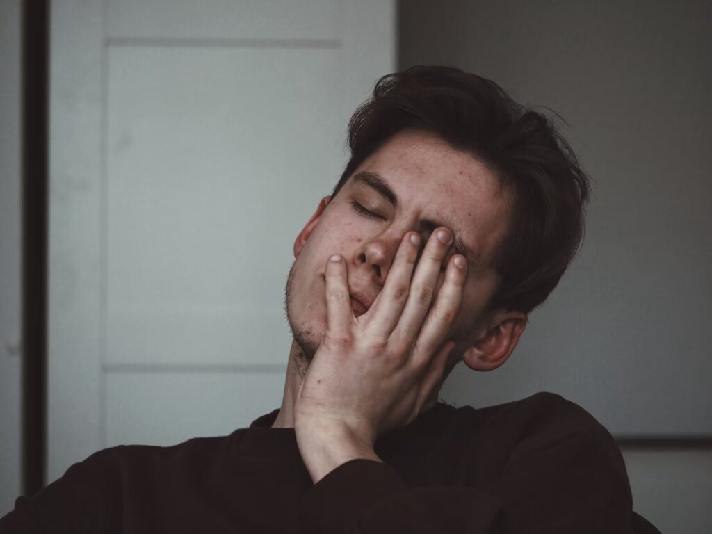 A person holding their face in their hand, looking frustrated and anxious.