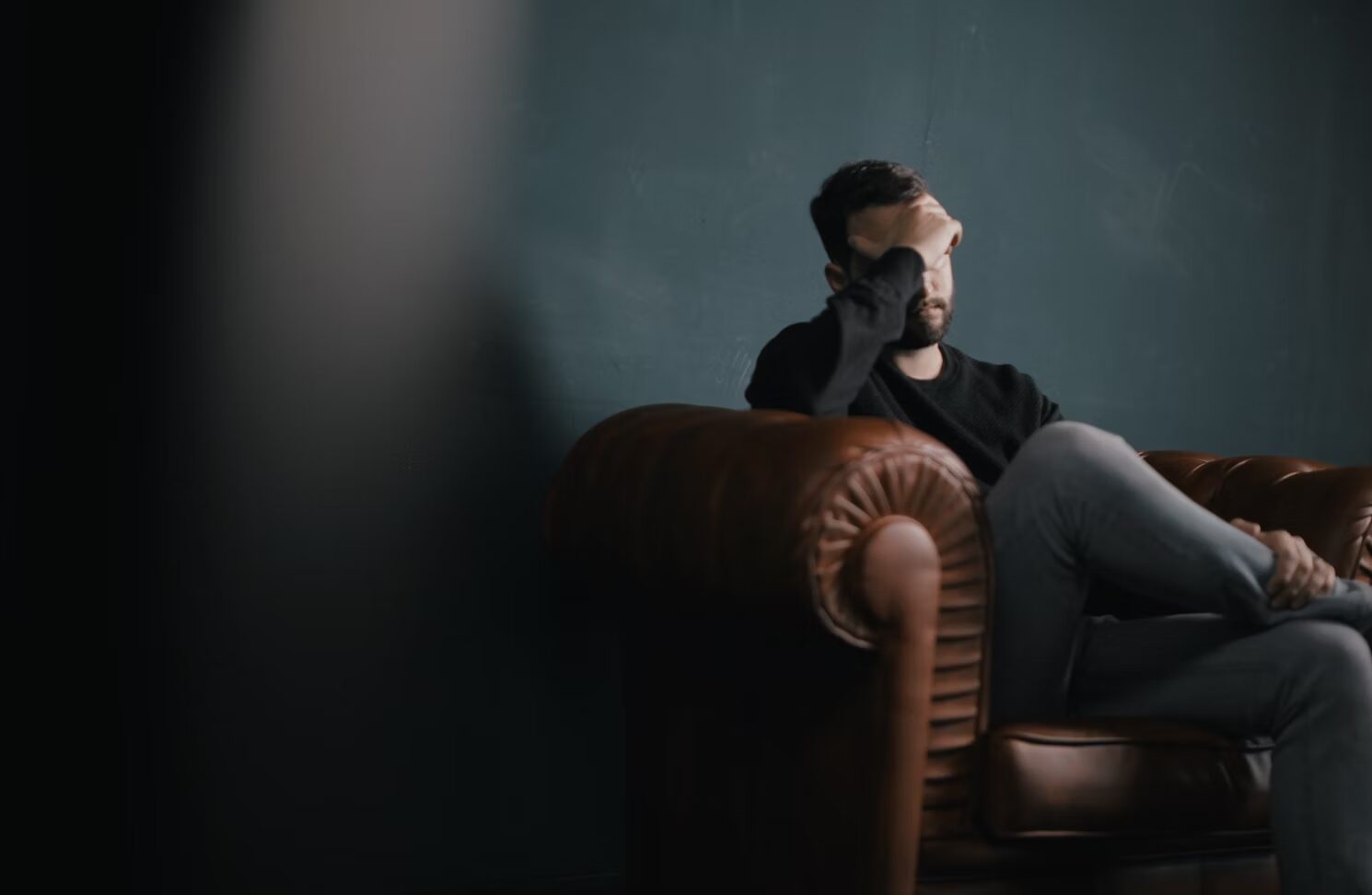 An image of a man holding his head in a therapy session