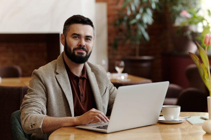 An image of a man using a laptop while sitting at a table