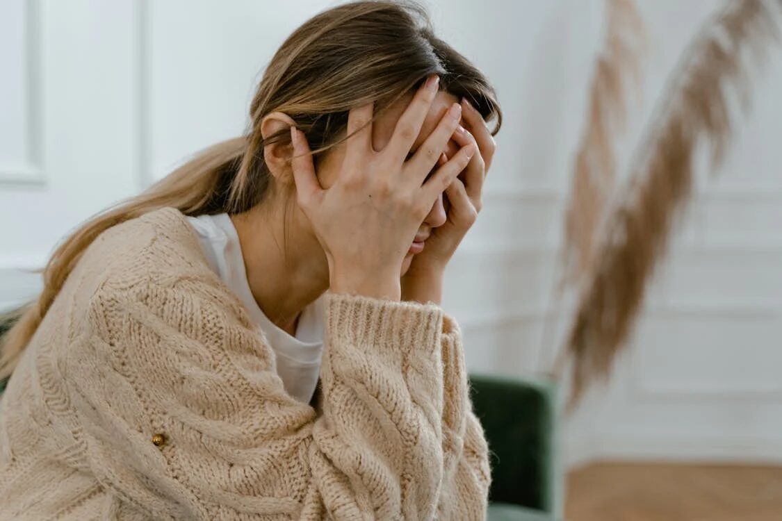 An image of a woman sitting with her head in her hands