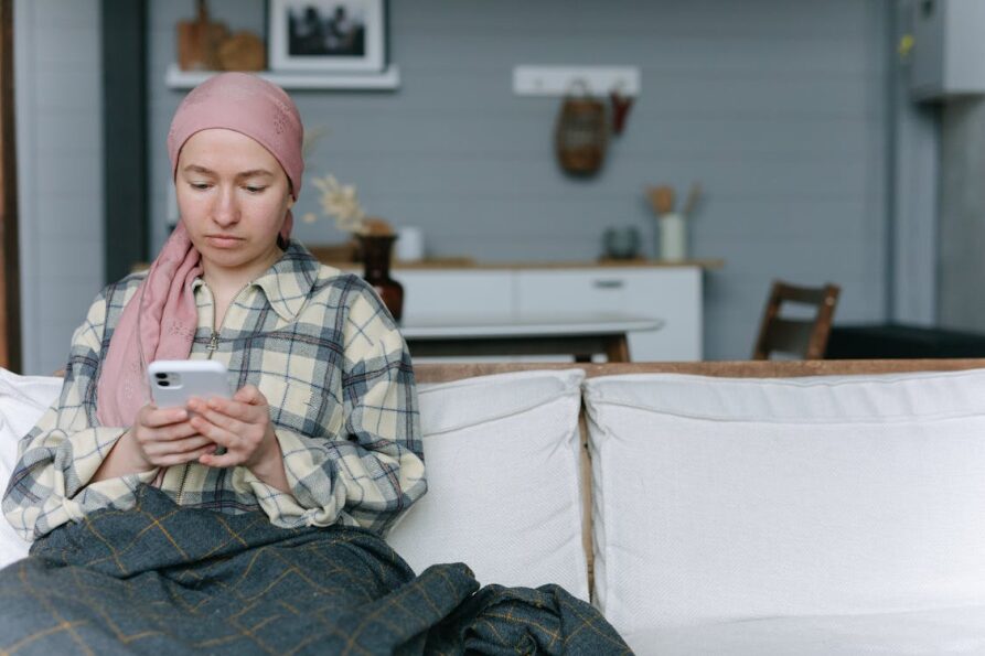 An image of a woman using her phone while sitting on the couch