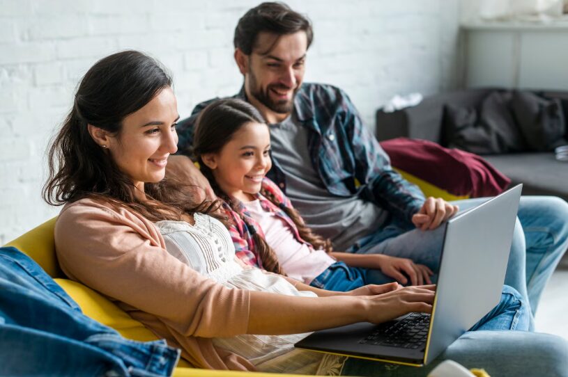 A blended family smiling together during a virtual therapy session on a laptop