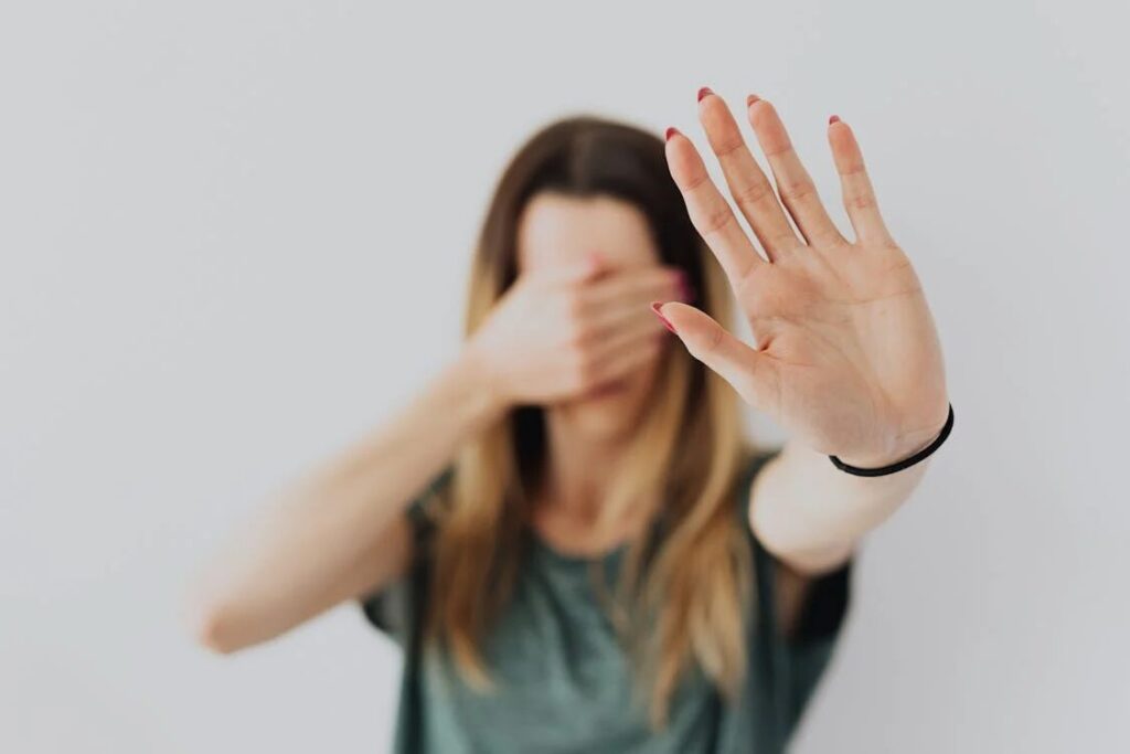 Woman avoiding eye contact with a hand raised