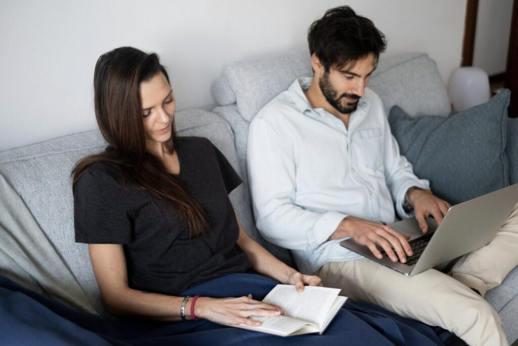 A couple sitting on a couch, preparing for their telehealth couples therapy session.