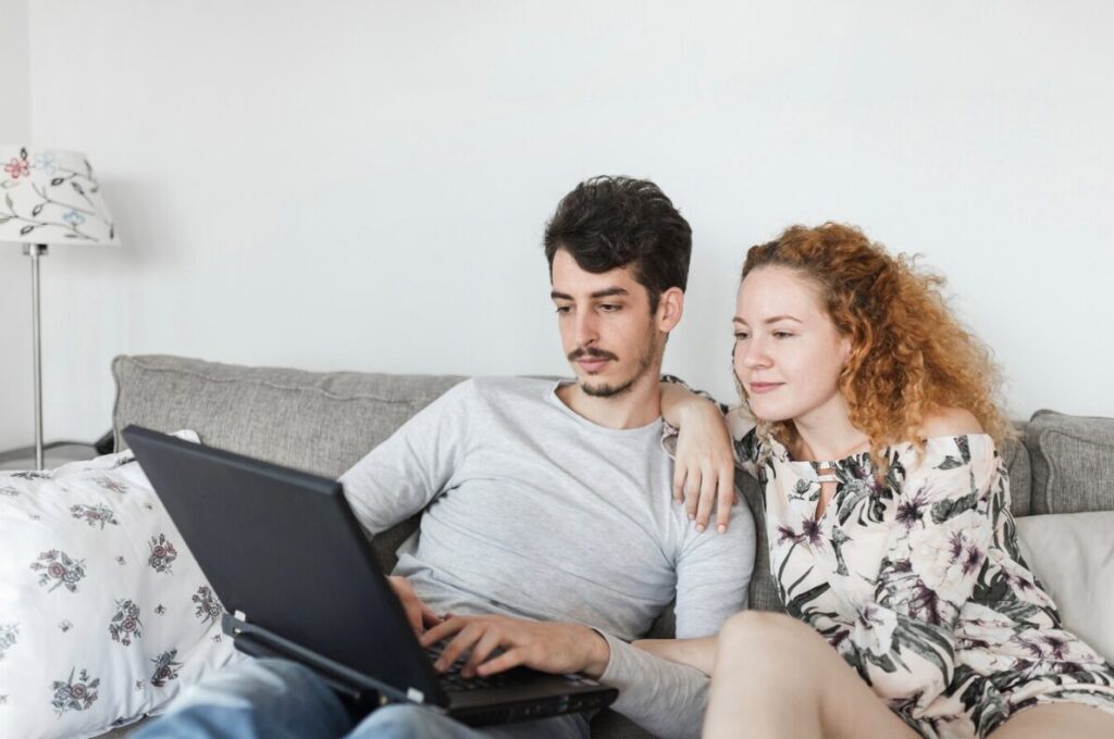 A couple speaking with a telehealth couples therapist at home via a laptop.
