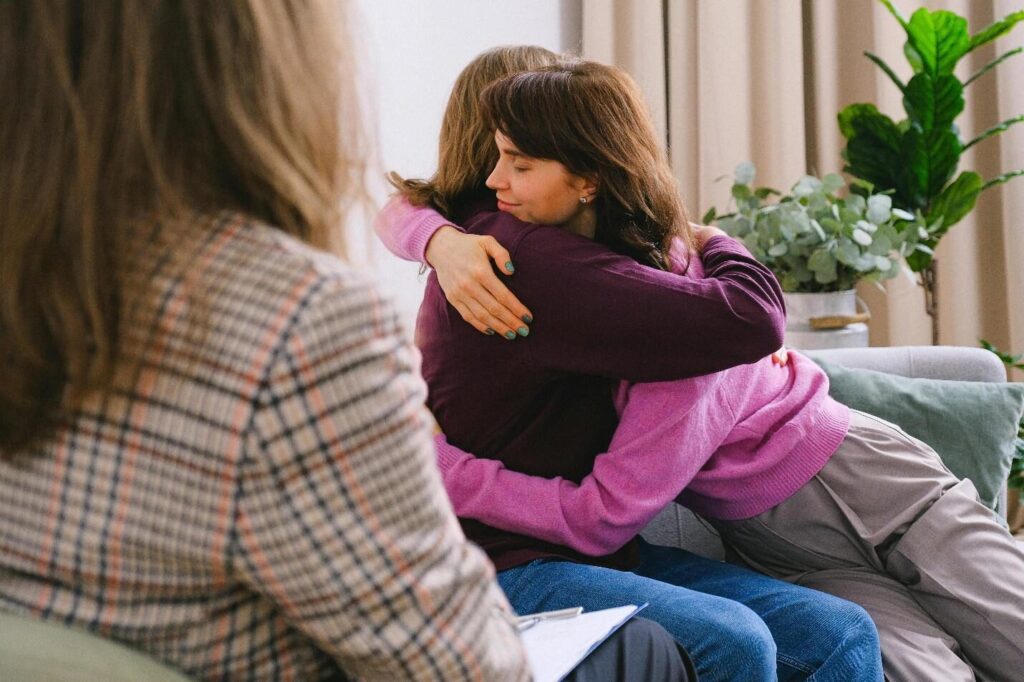 A picture of 2 people hugging during a therapy session