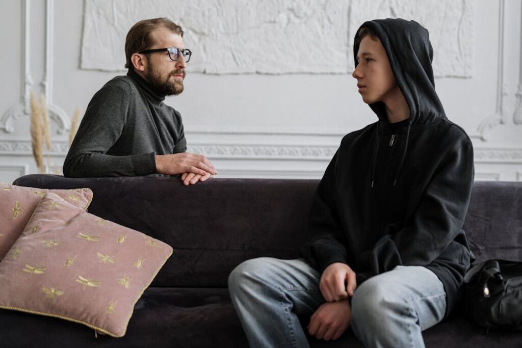 A therapist talking with a teenage boy during a counseling session.