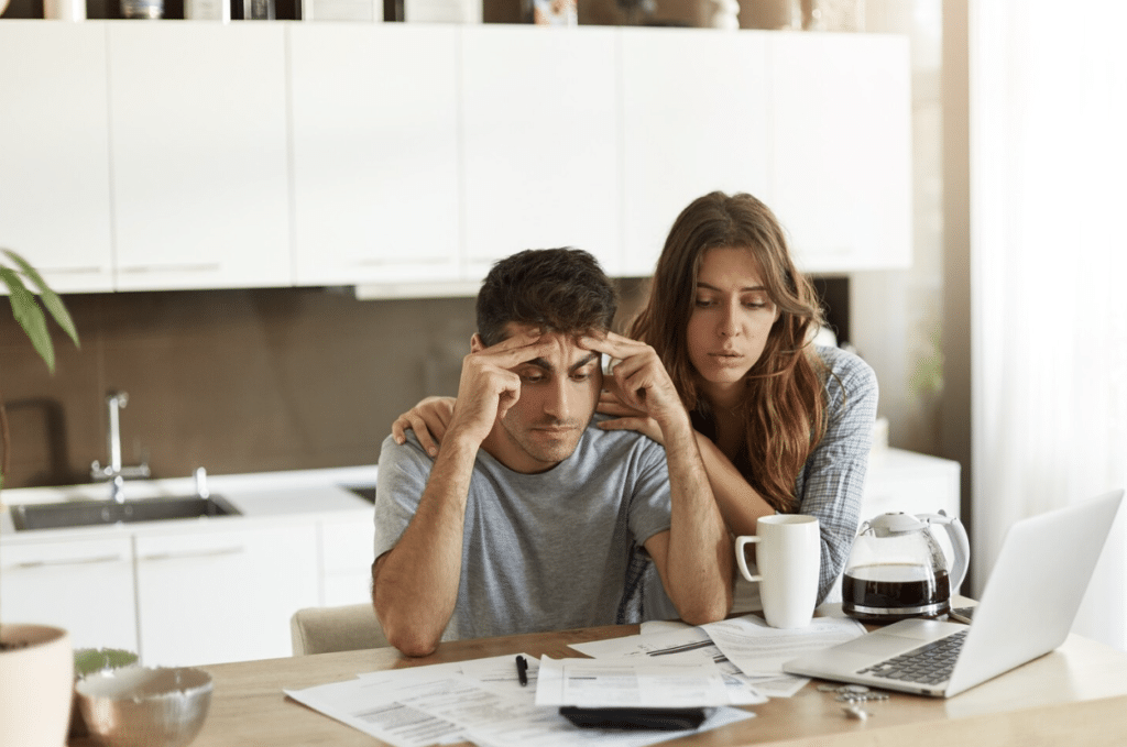 A young couple feeling stressed while checking their monthly budget.